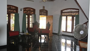 A room with a ceiling fan, a sofa, a chair, and a fan on the floor. - Villa Relax (Galle)