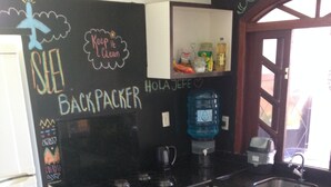 A compact kitchen with a blackboard, a water dispenser, a microwave, and a sink.
