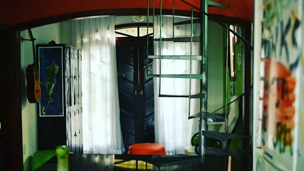 A room with a curved wall, a staircase, a map on the wall, and a refrigerator with a floral design.