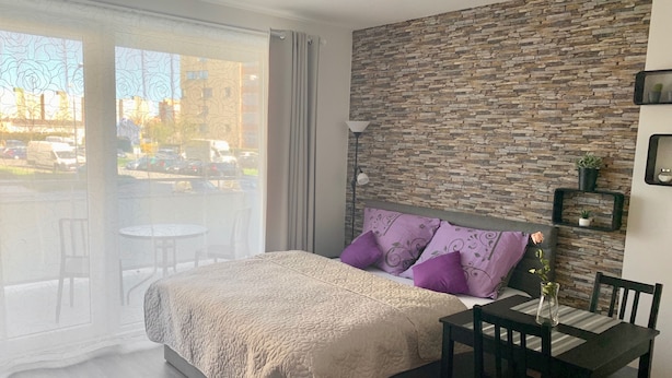 Un dormitorio con cama, una mesa de comedor, sillas, una pared de piedra y vistas al exterior.