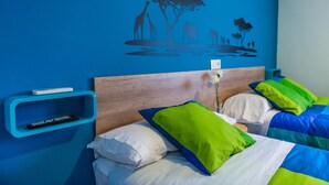 Une chambre avec un mur bleu, une tête de lit en bois et un lit agrémenté d’oreillers blancs et verts.