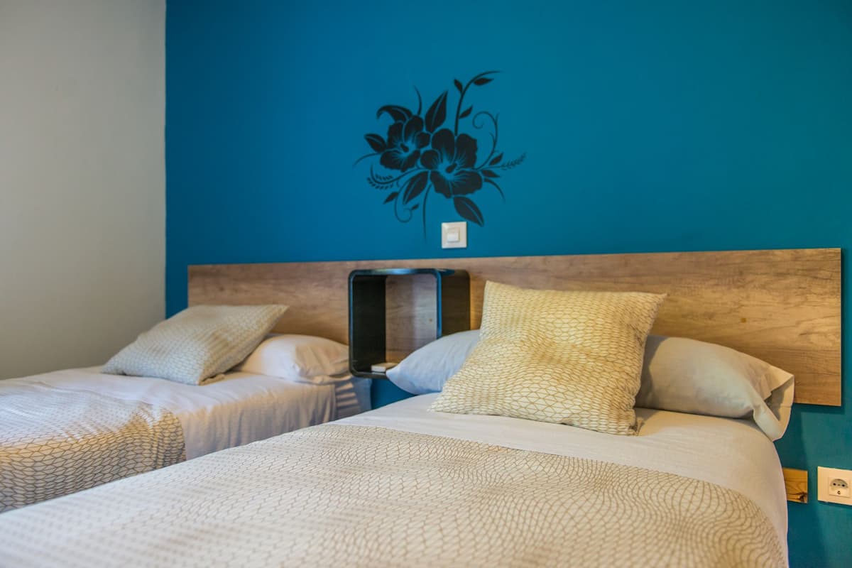 Une chambre d’hôtel avec deux lits, chacun doté d’une tête de lit, et un motif floral décoratif fixé au mur.