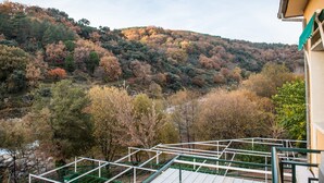 Une vue d’une colline parée des couleurs de l’automne, d’un escalier menant à un bâtiment et d’une rivière au premier plan.