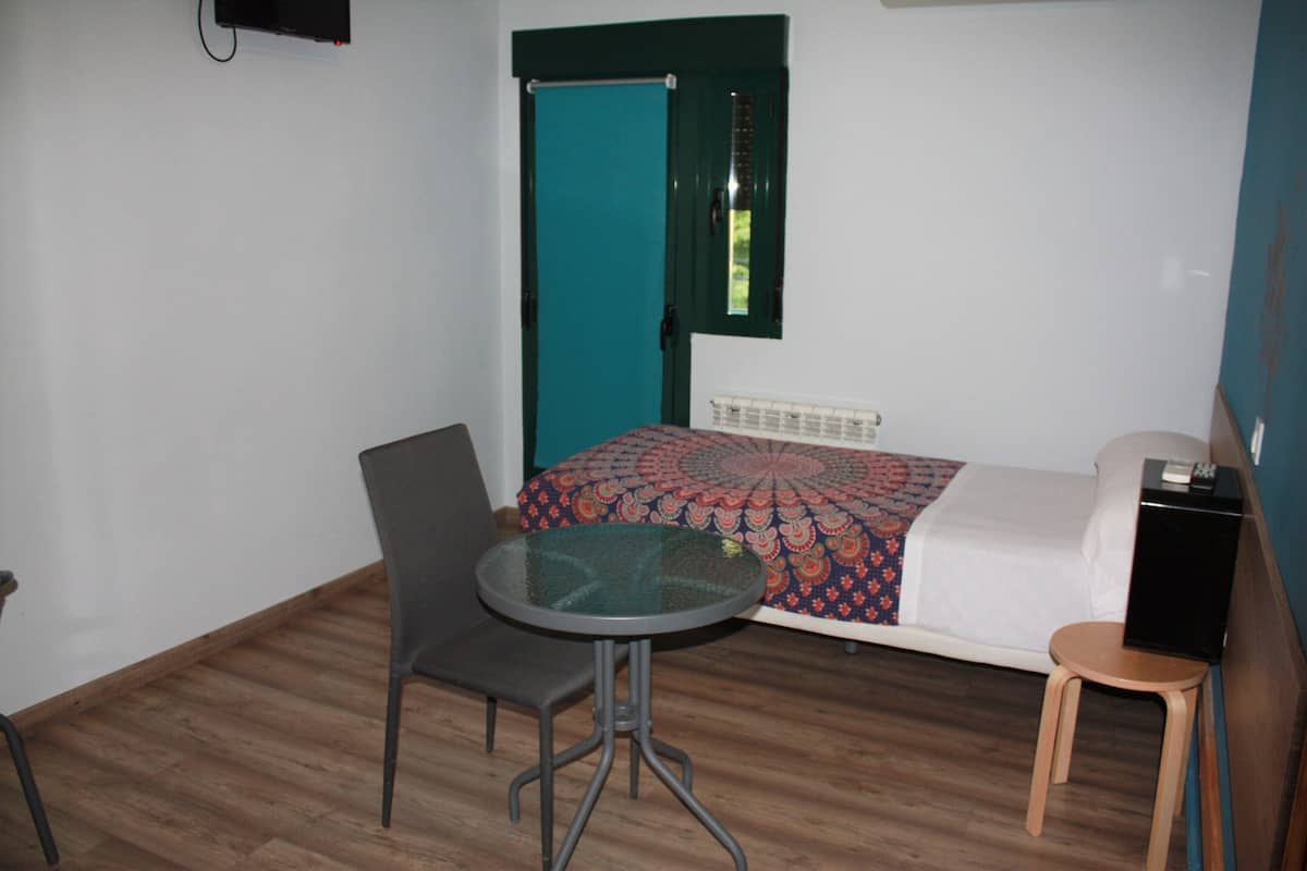 Une petite pièce avec un lit, une table et deux chaises.