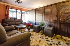 A cozy lounge area with a sofa set, a small round table with a plant, and a potted plant. - Hostal La Pastora (Candeleda)