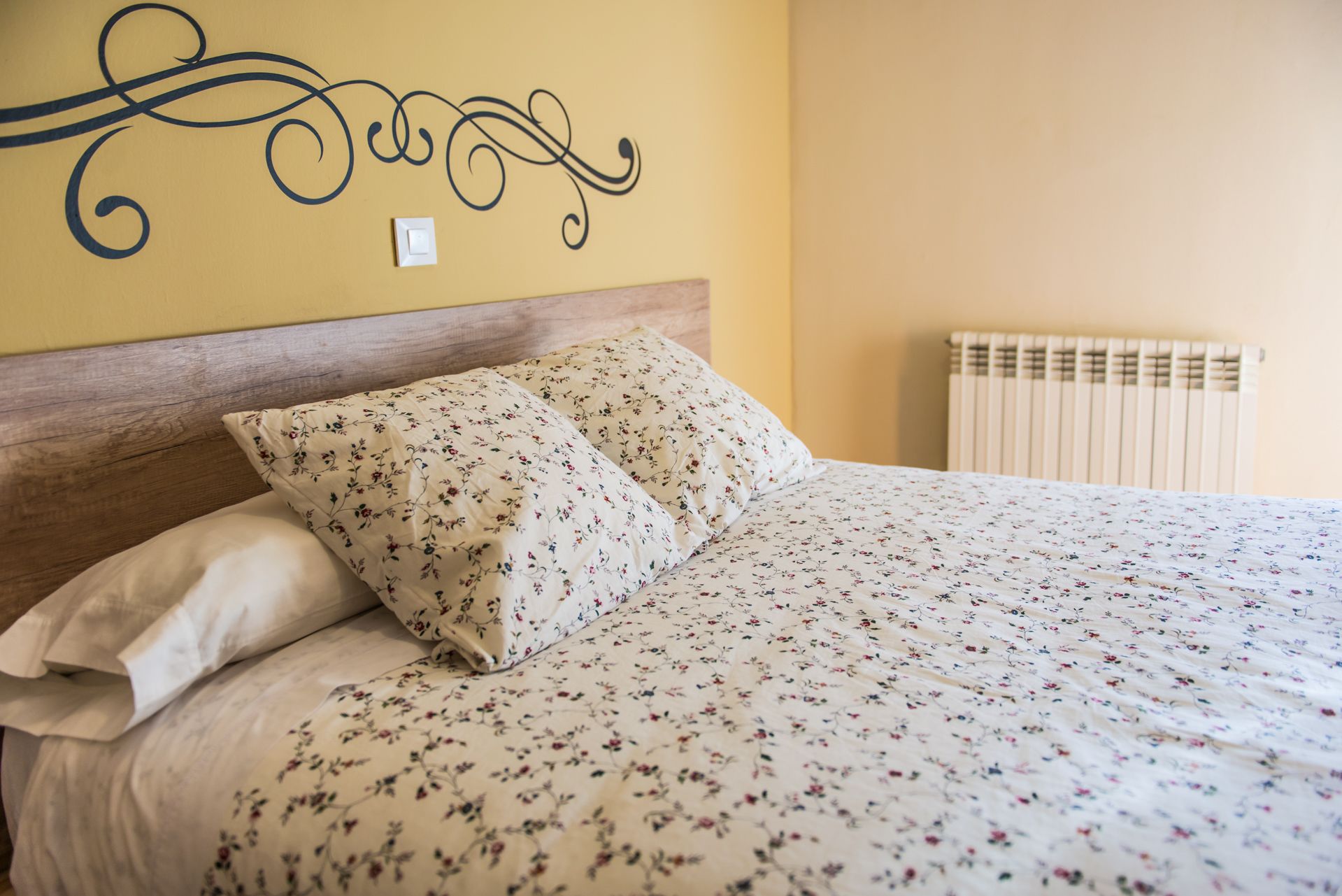 Una cama con ropa de cama floral y un cabecero de madera.