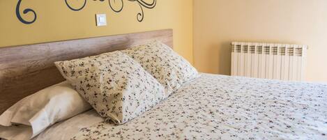 Una cama con ropa de cama floral y un cabecero de madera.