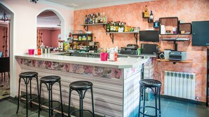 Un espace bar avec des tabourets, un comptoir et des étagères remplies de bouteilles et de collations.