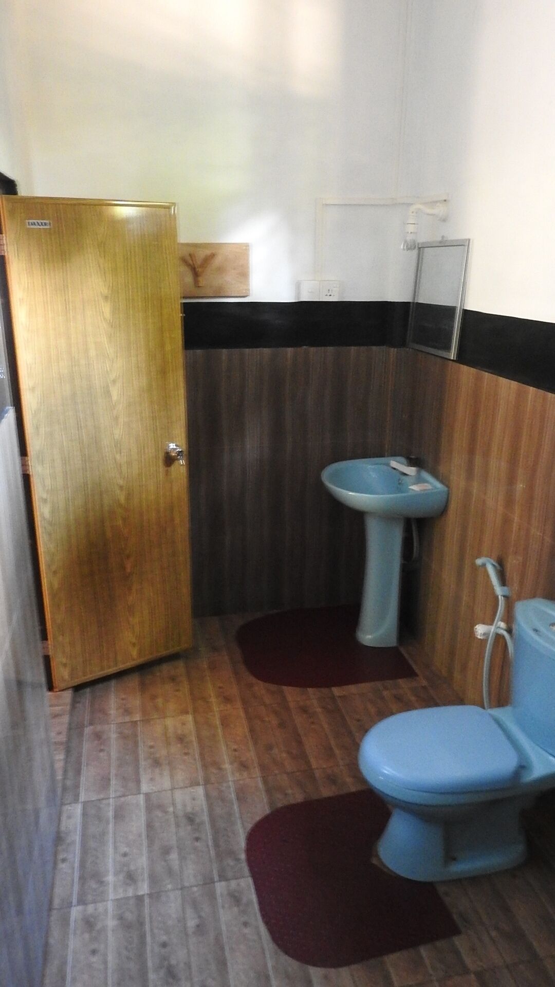 A small bathroom with a wooden door, a sink, and a toilet.