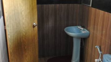A small bathroom with a wooden door, a sink, and a toilet.
