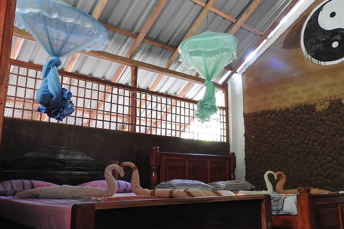A room with a bed, a wooden headboard, a wall with a textured pattern, and a large Yin-Yang symbol on the wall.
