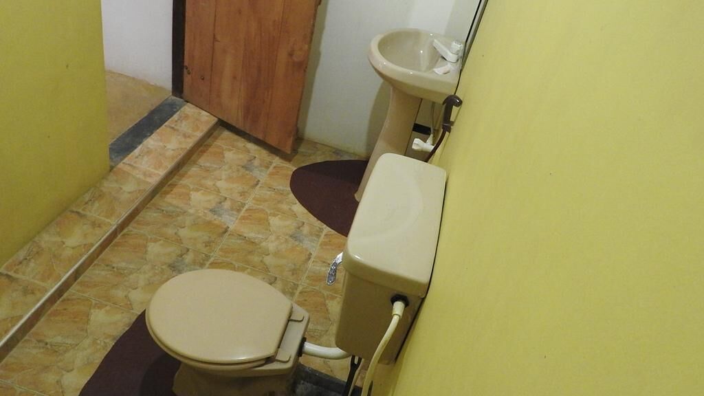 Ein kleines Badezimmer mit Toilette, Waschbecken und Holztür.