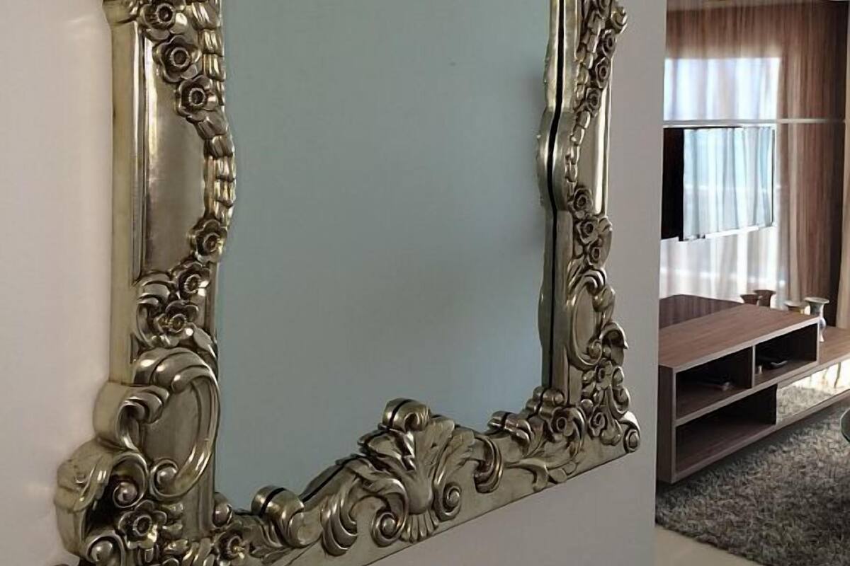 Un grand miroir décoratif, orné de motifs complexes, est accroché au mur.