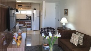 Una sala de estar moderna con un sofá marrón, una mesa de centro de vidrio y una zona de comedor con una silla y una pequeña mesa.