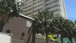 Un hotel moderno de gran altura con varias plantas, balcones y un cielo azul despejado.