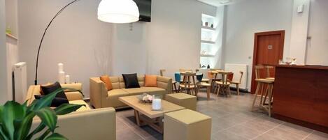 Un vestíbulo de hotel moderno con sofás, un mostrador de recepción y un área de comedor.