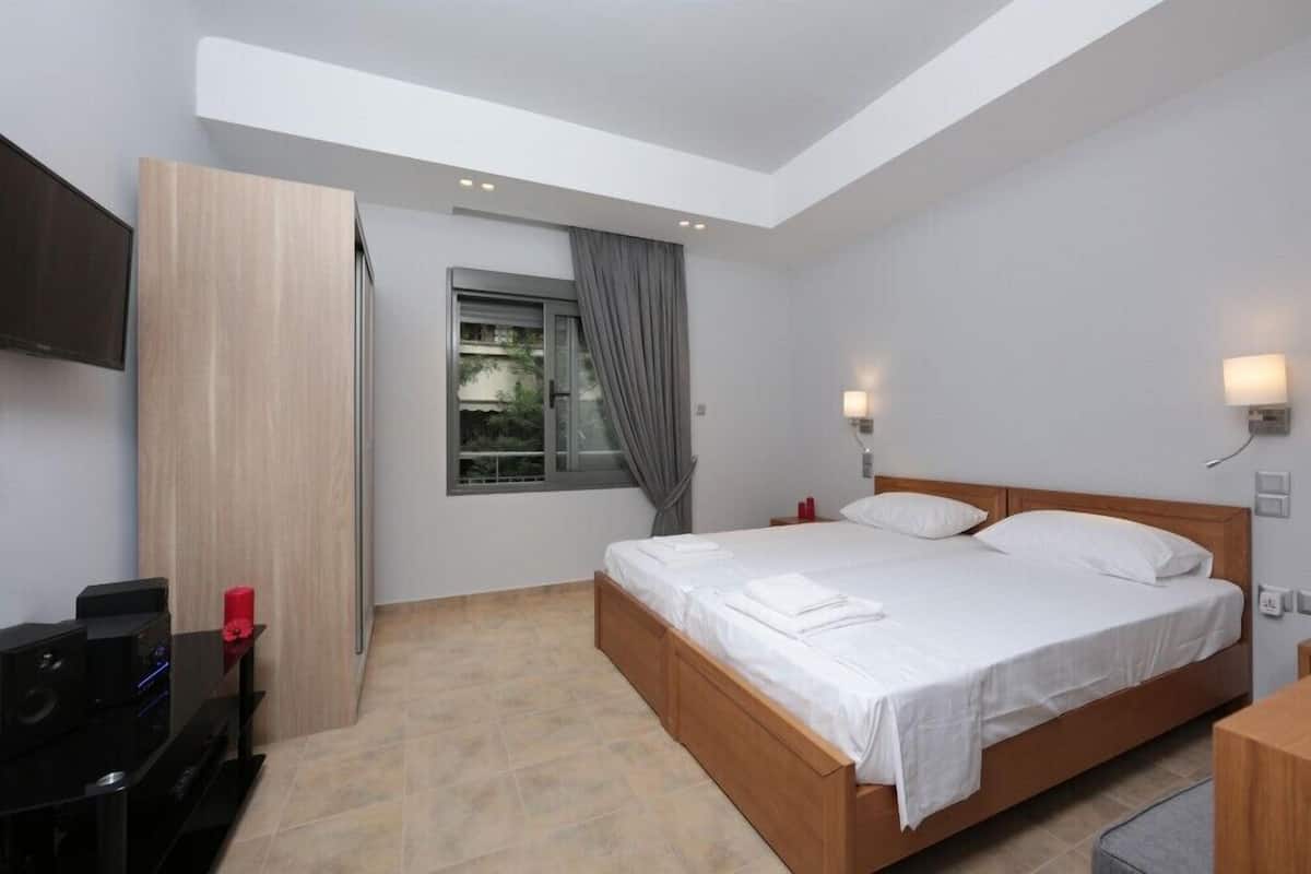 A modern bedroom with a wooden bed, a TV, and a window with curtains.