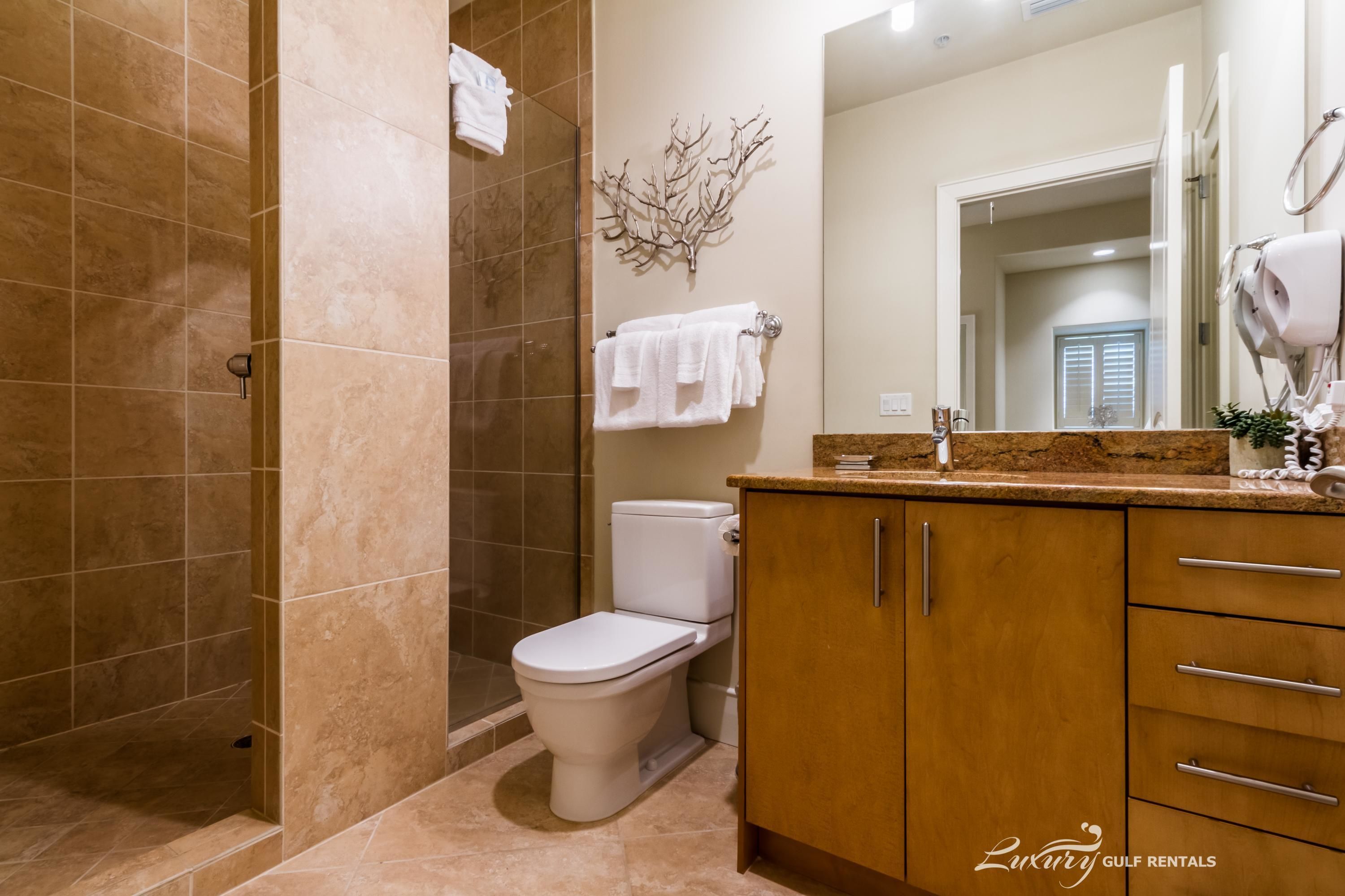 A bathroom with a shower, toilet, and vanity with cabinets and a mirror.