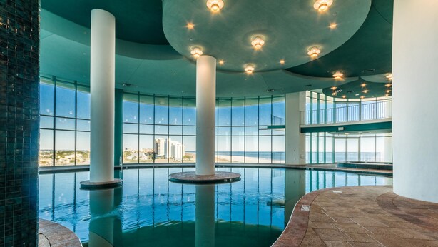 An indoor swimming pool with clear views of the city skyline, large columns, and a modern ceiling design. - Turquoise Place 2806C (Orange Beach)