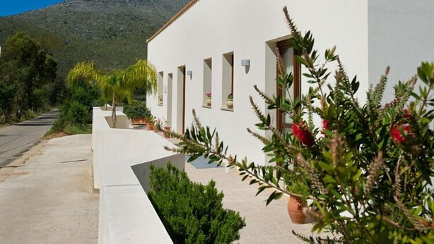 Un edificio blanco con muchas ventanas y una montaña al fondo.