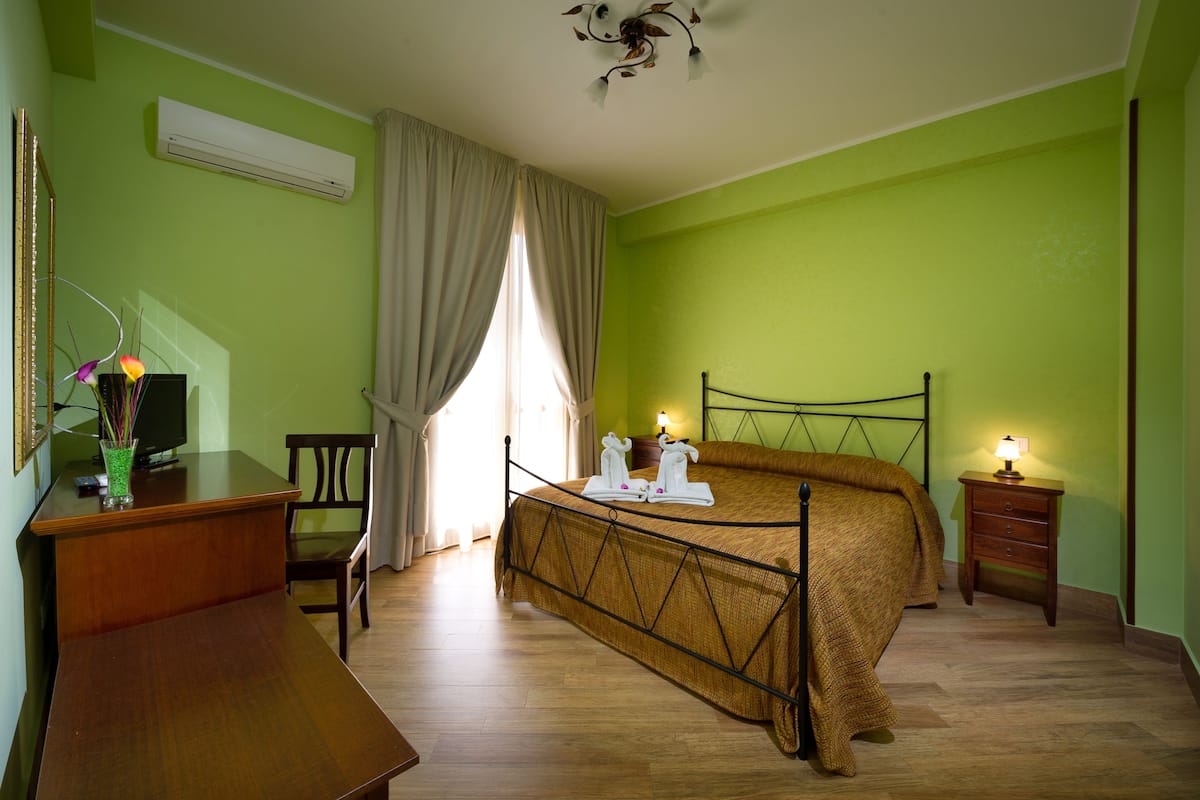 Une pièce comprenant un lit, un bureau, une chaise, une table de chevet et une lampe.