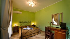 Un dormitorio con una cama, lámparas de noche, un escritorio con silla, televisor y un espejo.