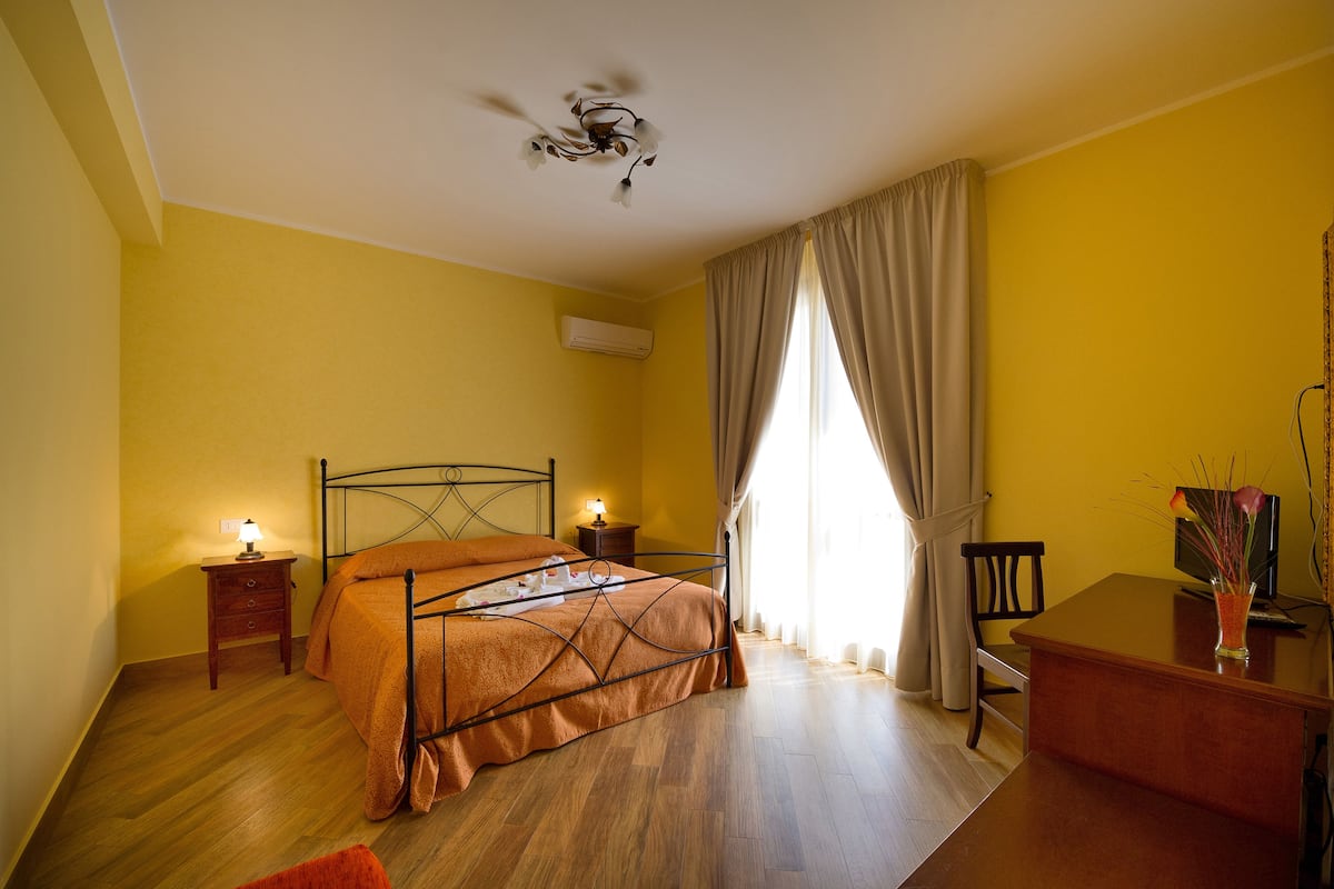 Une chambre à coucher avec un lit, des tables de chevet, un bureau et une chaise.