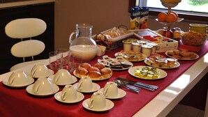 A buffet table with various food items and beverages, including a pitcher of milk, pastries, and a fruit bowl. - Marcella House (Cagliari)
