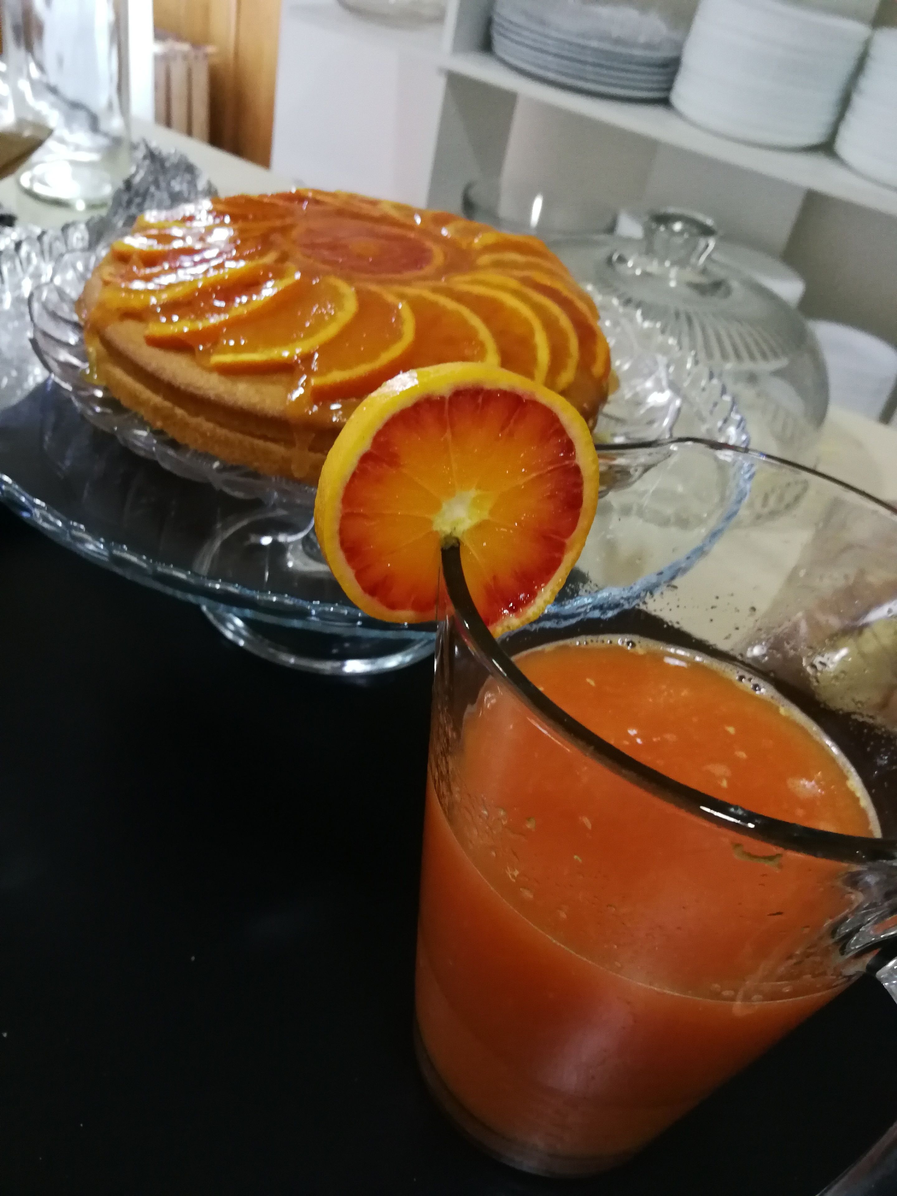 A breakfast setting with a fruit-topped dish and a glass of orange juice.