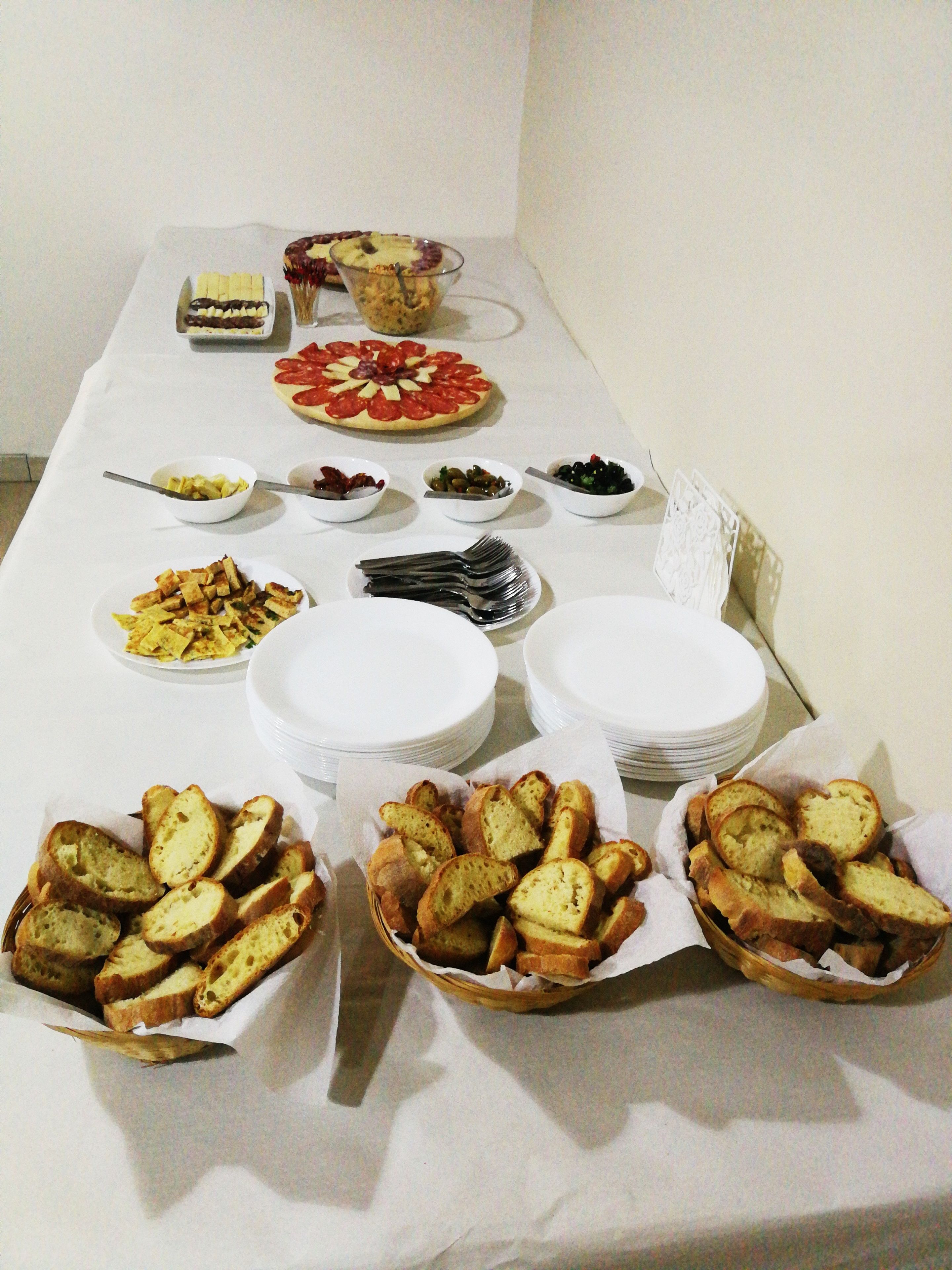Una mesa de buffet con diversos platos, incluyendo pizza, pan y ensaladas.