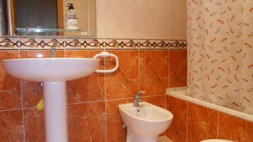 Une salle de bain avec un lavabo sur colonne blanc, un petit bidet blanc et des toilettes.
