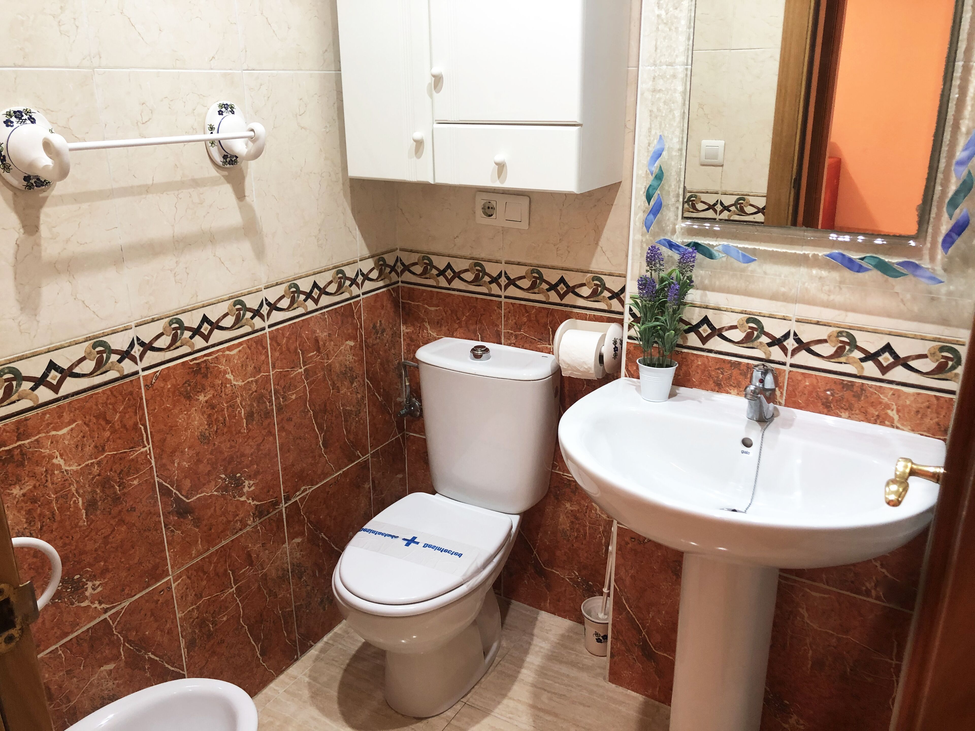 Une salle de bain avec des toilettes, un lavabo et un miroir.