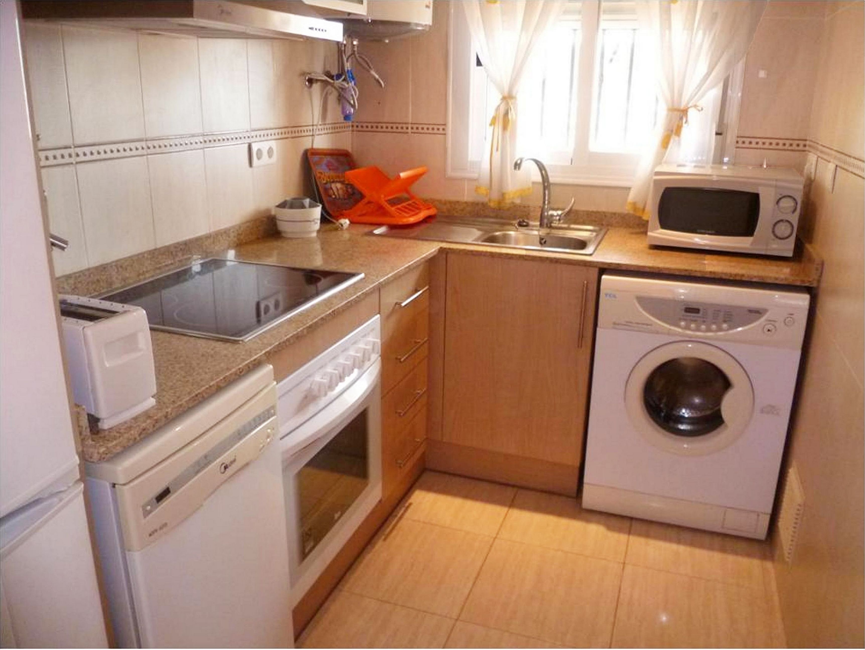 Eine kleine Küche mit Spüle, Mikrowelle, Waschmaschine und Toaster.