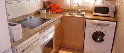 A compact kitchen with a sink, microwave, washing machine, and a toaster.