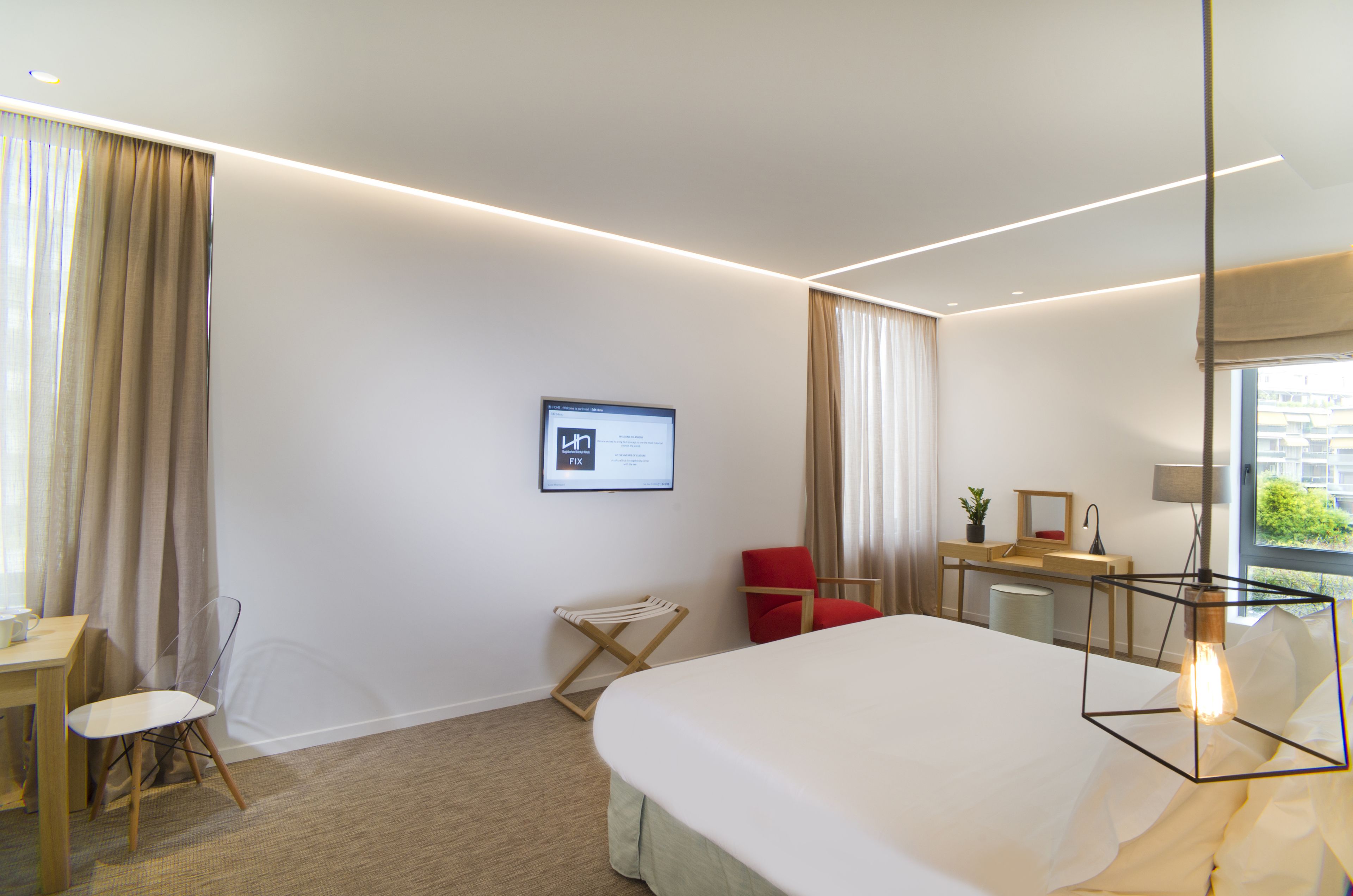 Une chambre d’hôtel moderne équipée d’un lit, d’un bureau, d’une chaise et d’une lampe de bureau.