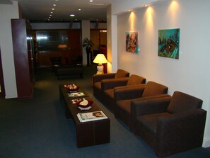 Un hall d'hôtel comprenant un comptoir d'accueil, un espace salon et des œuvres d'art accrochées aux murs.