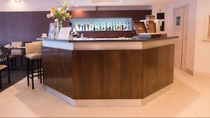 A reception area with a wooden counter, a glass display case with various bottles, and a seating area with chairs and a table. - Gran Hotel Continental (Mar del Plata)