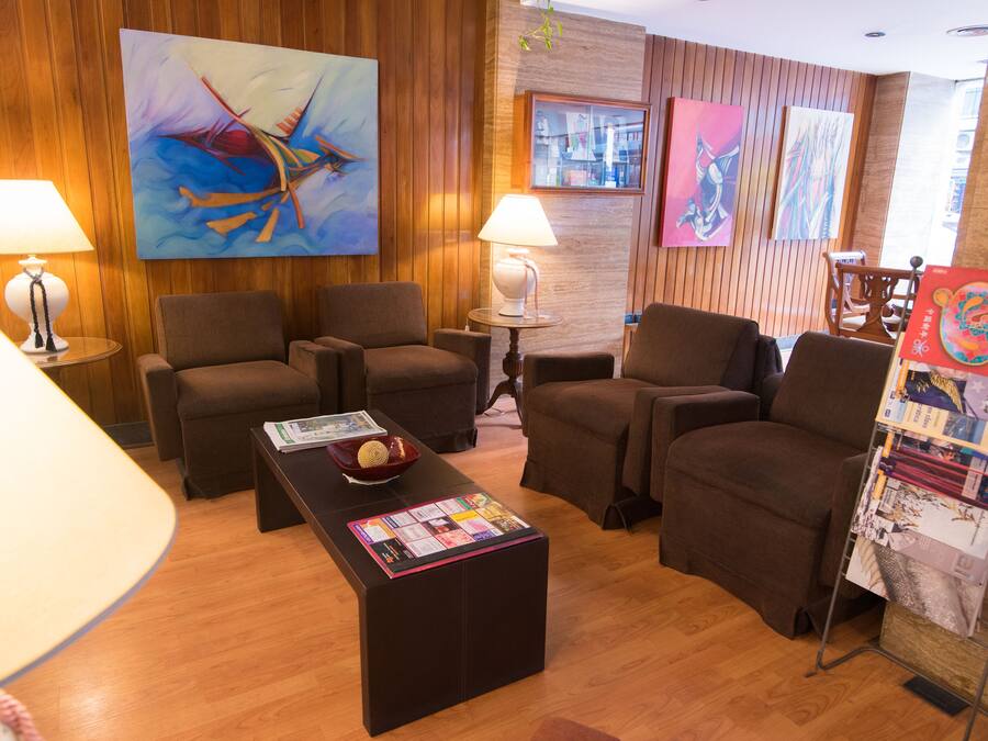Un moderno vestíbulo de hotel con paneles de madera, asientos cómodos y obras de arte en las paredes.