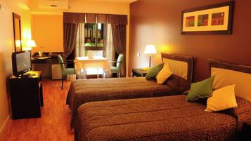 Habitación de hotel con dos camas, un escritorio con silla, un televisor y una ventana con cortinas.