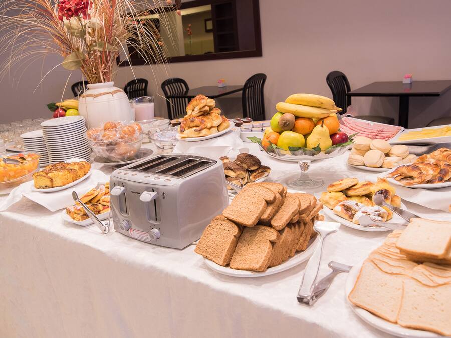 A buffet table with various food items, including bread, fruits, and pastries.