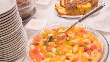 A buffet table with various food items including a fruit salad and pastries.