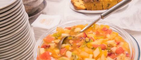 A buffet table with various food items including a fruit salad and pastries.