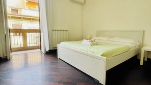 A bedroom with a bed, a bedside table, a radiator, and a view of the outside. - Mamamia #Teatro Massimo (Palermo)