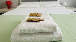 A neatly made bed with a green bedspread and white pillows, a white headboard, and a red lamp on the nightstand. - Mamamia #Teatro Massimo (Palermo)