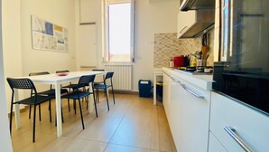 A compact kitchen with a dining area, a window, and a tiled backsplash. - Mamamia #Teatro Massimo (Palermo)