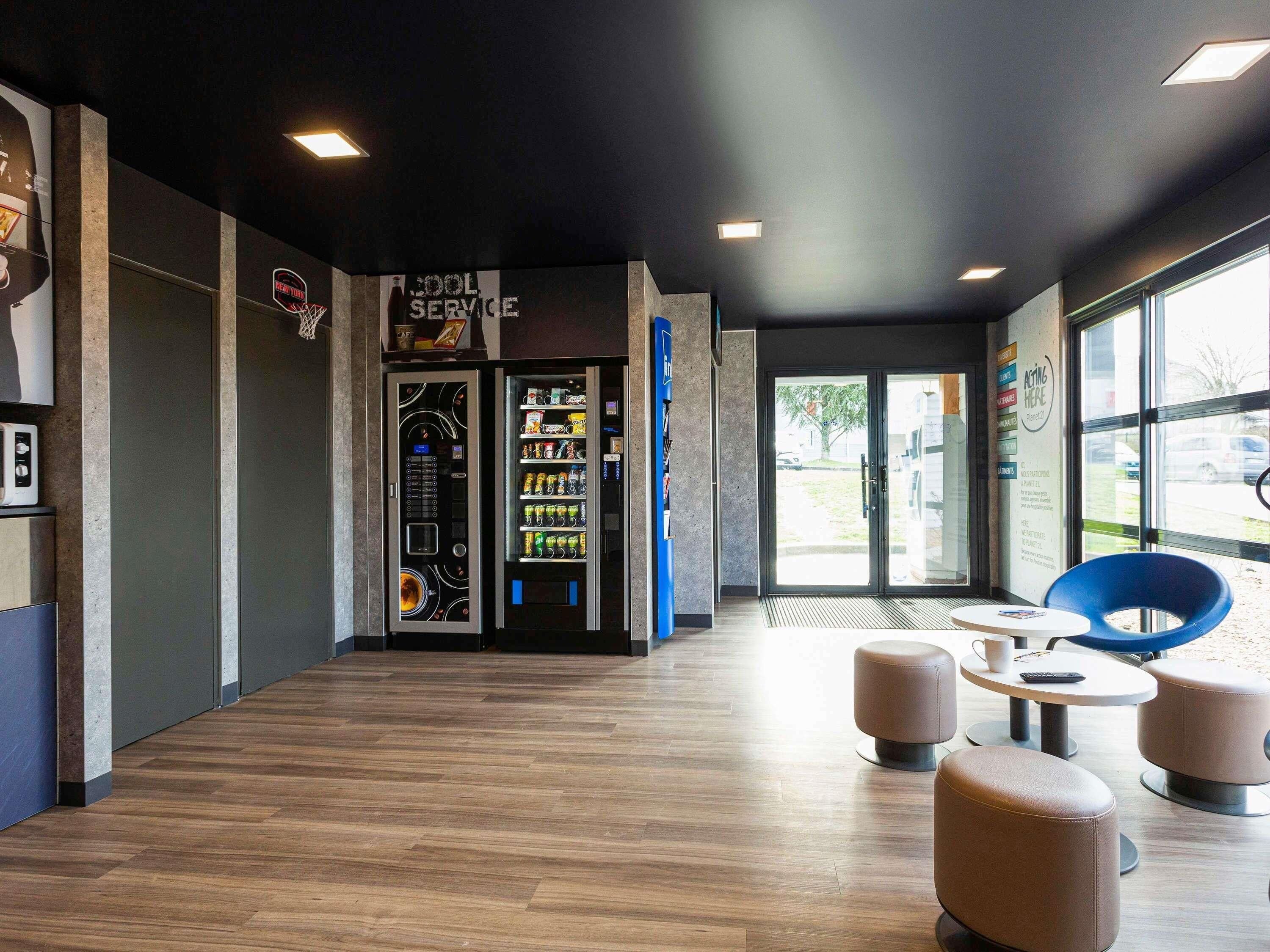 A modern interior with vending machines, seating area, and large windows.