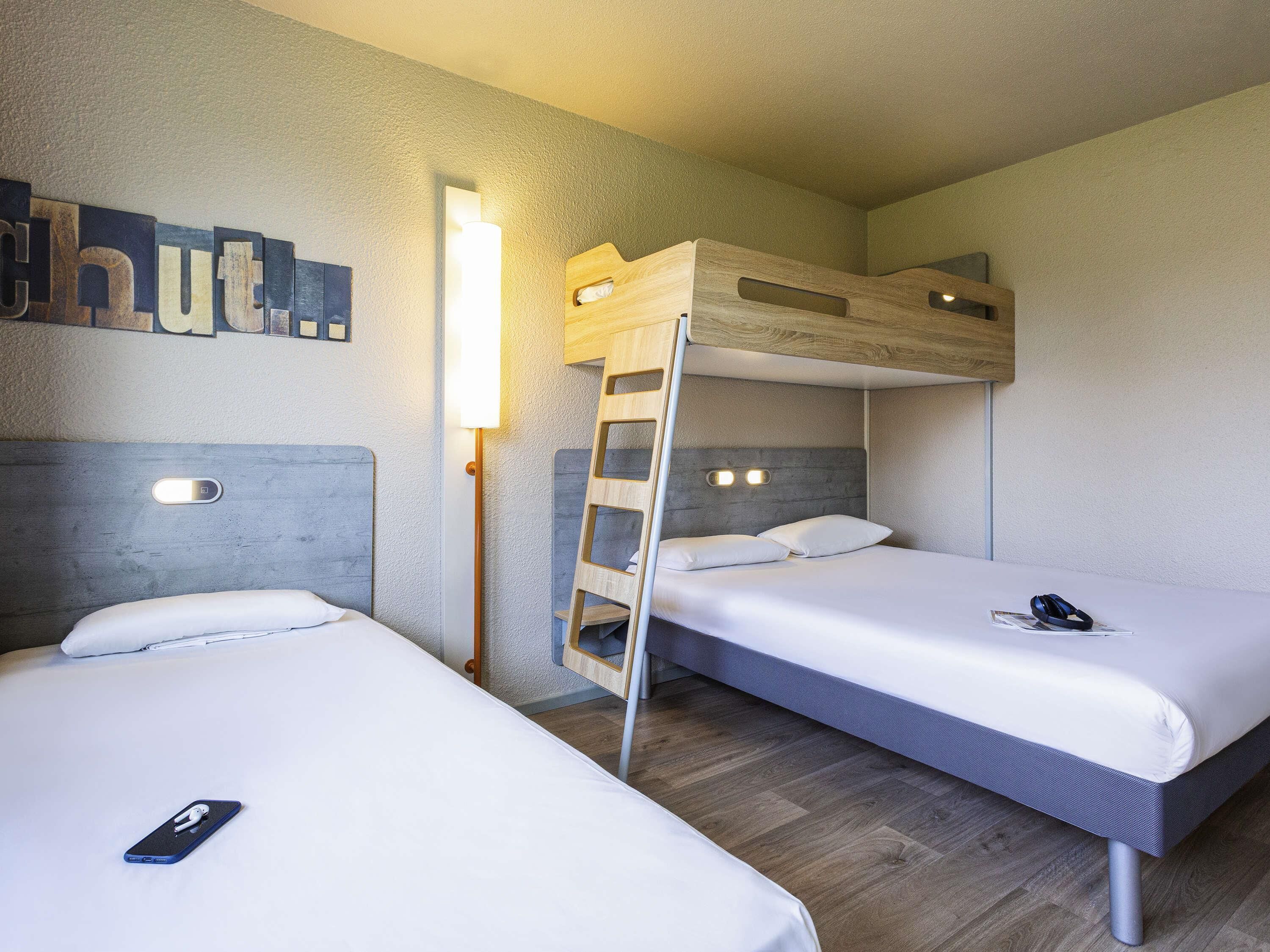 Habitación con literas, una mesita de noche y una lámpara fijada a la pared.