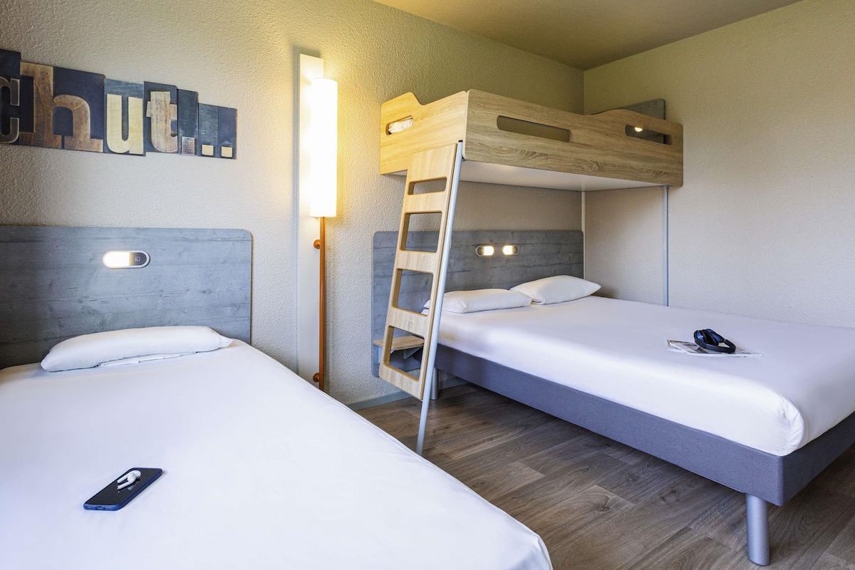 Habitación con literas, una mesita de noche y una lámpara fijada a la pared.