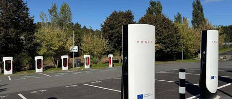 Un espace de stationnement équipé de plusieurs bornes de recharge pour véhicules électriques Tesla.