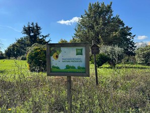 A sign in a natural setting with a logo for ibis styles hotels, indicating a preserved nature area.